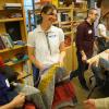 Laura Devendorf stands smiling in the Unstable Design Lab while holding a colorful woven form and showing it to guests