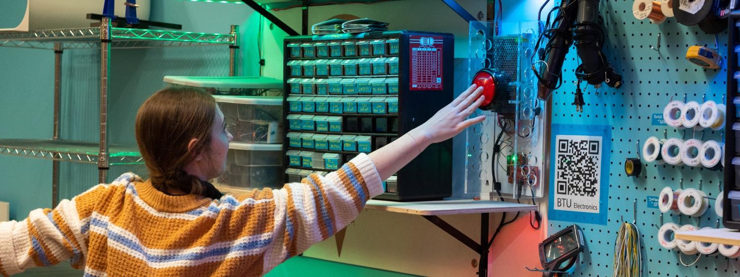 Student reaching for a big red button on the BTU Lab wall
