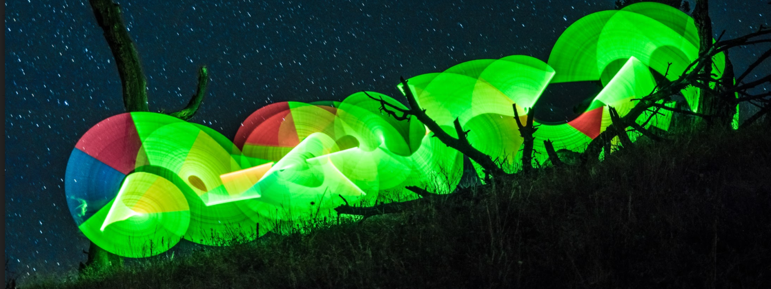 Digital image of a bright-green, caterpillar-like image against a starry night sky and bare trees.