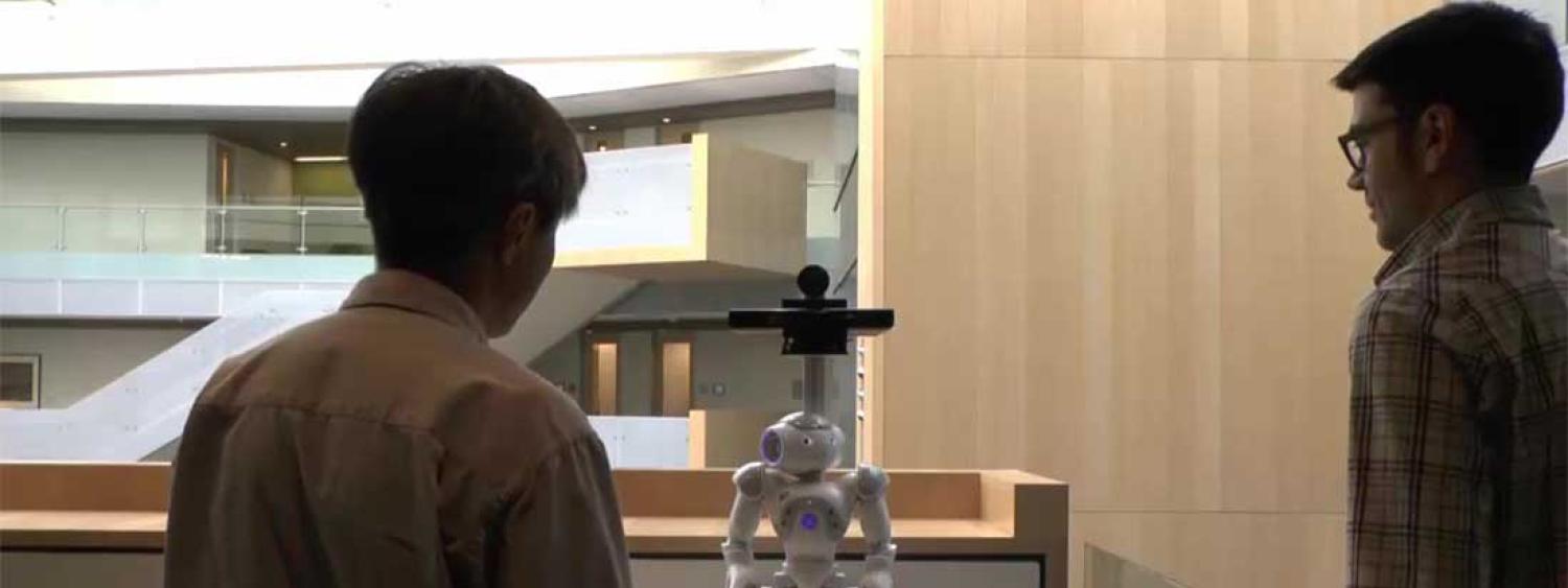 Two people look at a robot.