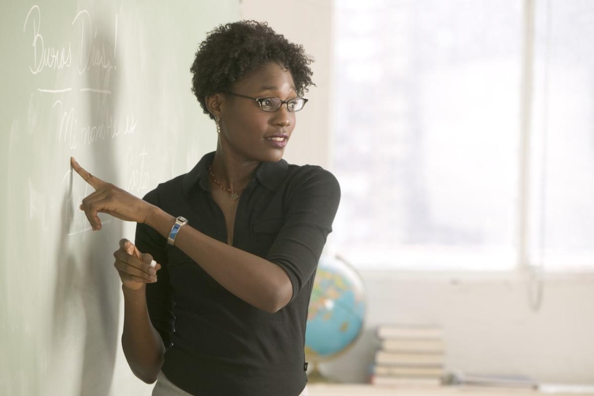 Woman pointing to black board