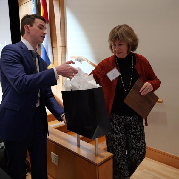 Excellence Awardee Cosetta Seno receives gift bag from student event coordinator Joe Muckle
