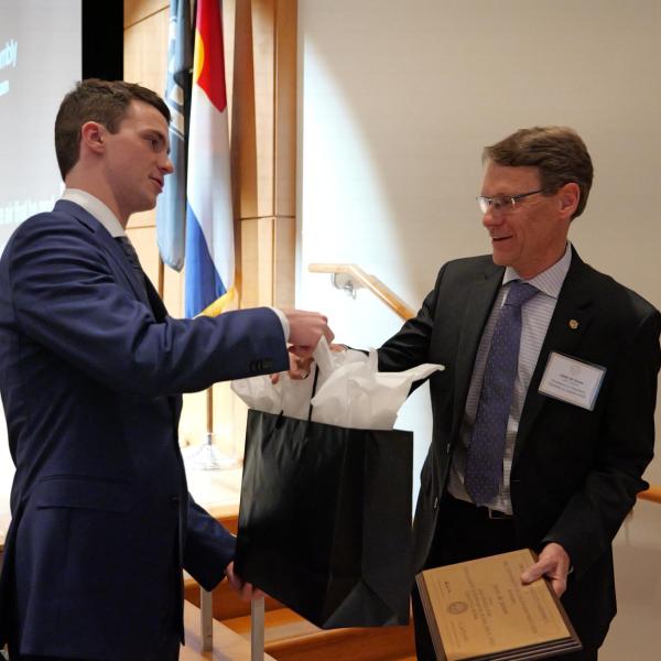 Excellence Awardee Joost de Gouw receives gift bag from student event coordinator Joe Muckle
