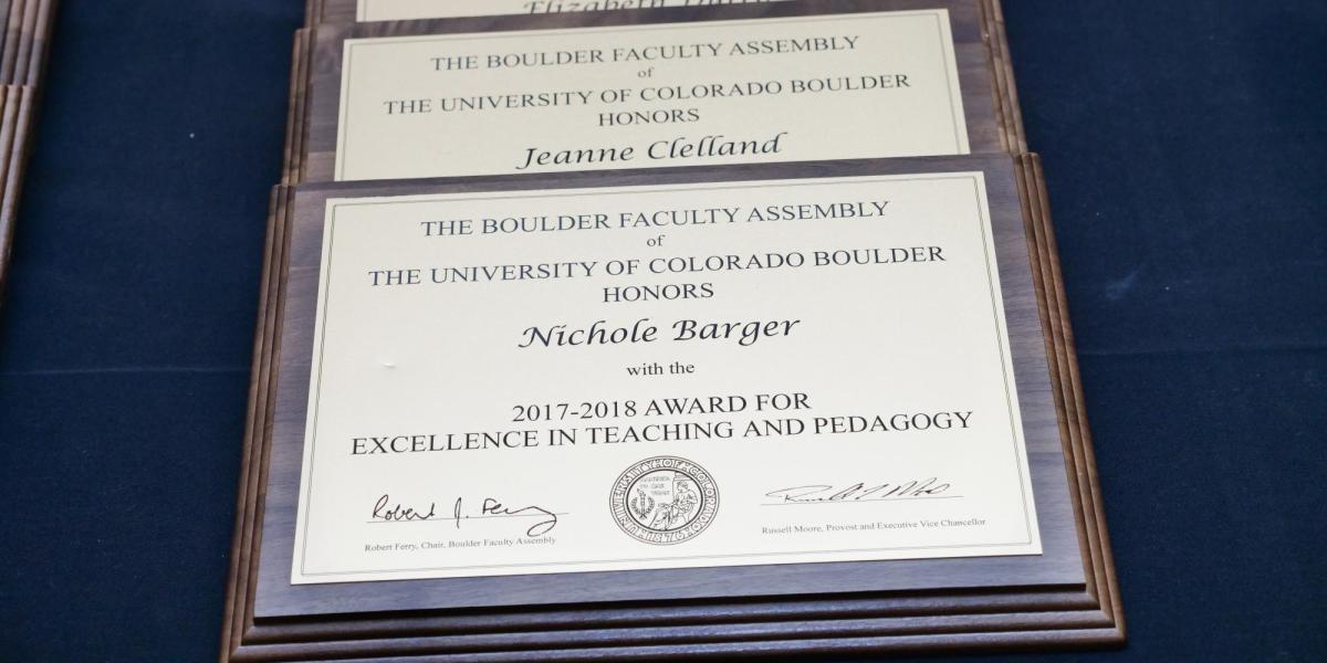 Several award plaques lined up on a blue table