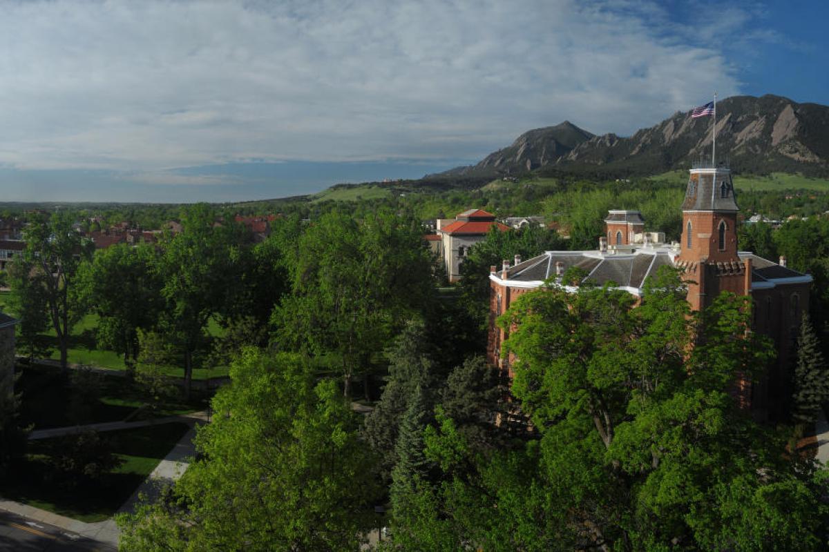 The brick building Old Main surrounded by lush green forests on a sunny day