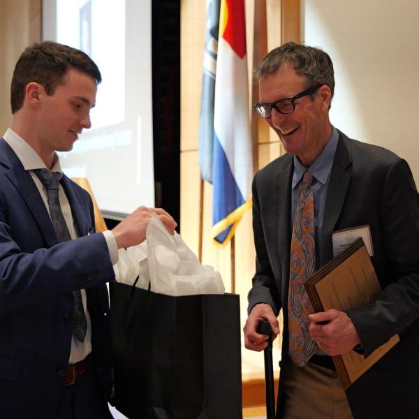 Excellence Awardee Jason Boardman receives gift bag from student event coordinator Joe Muckle
