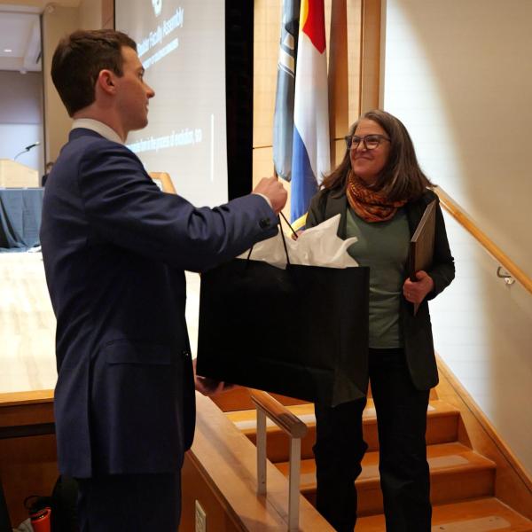 Excellence Awardee Rebecca Safran receives gift bag from student event coordinator Joe Muckle