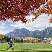 Flatirons in the fall, with a student walking by.