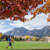 Flatirons in the fall, with a student walking by.
