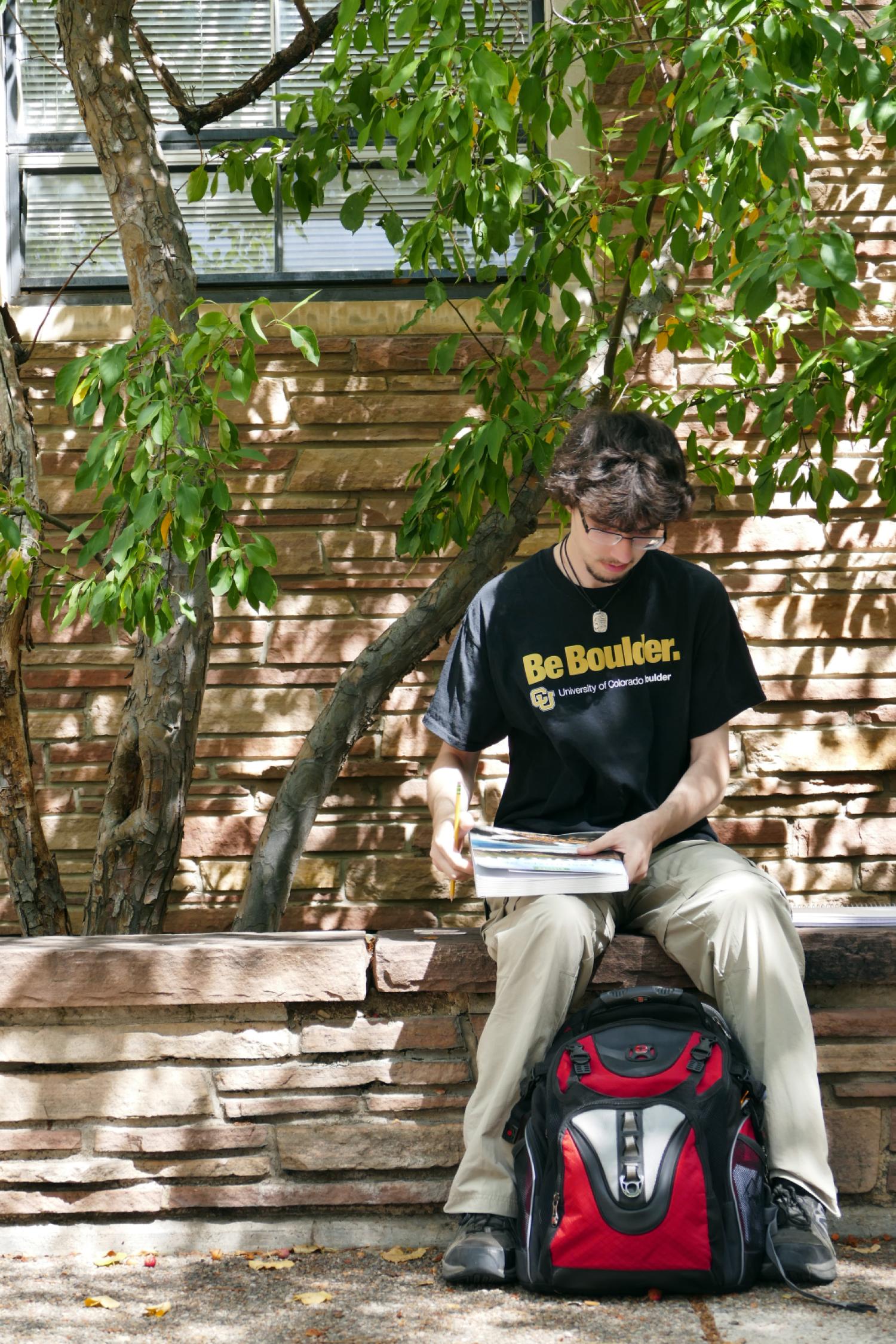 student studying with book (Photo by Glenn Asakawa/University of Colorado)