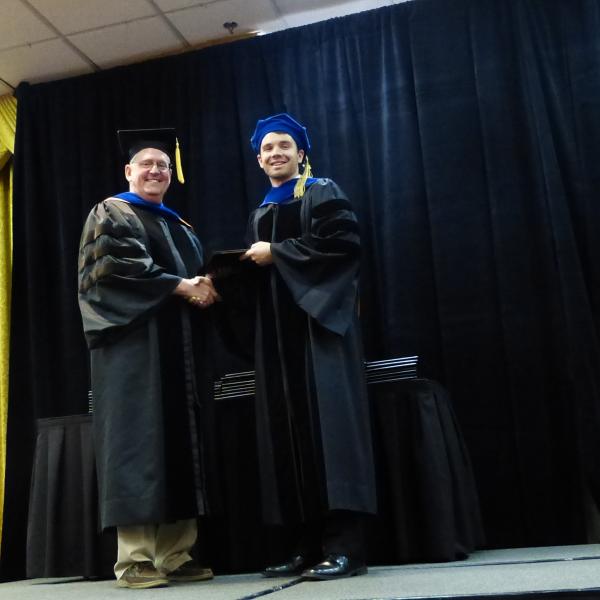 Chair, Carl Koval congratulating Ph.D. graduate XXX