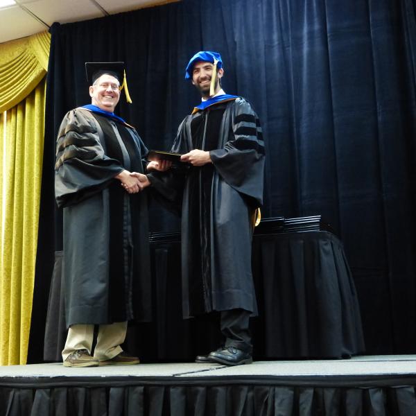 Chair, Carl Koval congratulating Ph.D. graduate Steven Strong