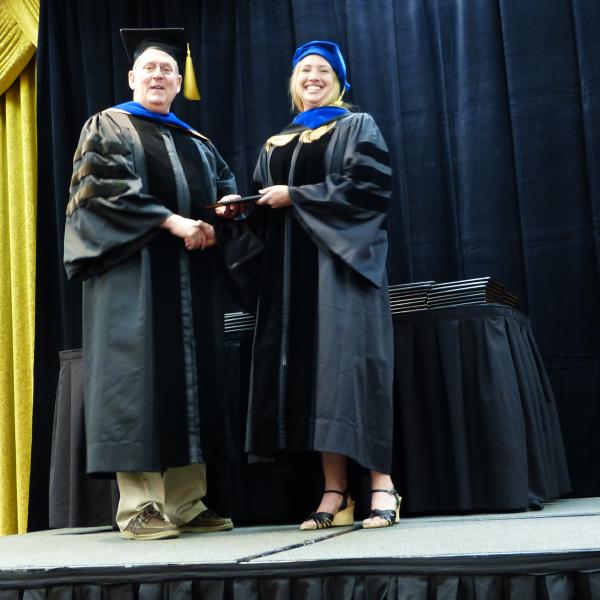 Chair, Carl Koval congratulating Ph.D. graduate Alexandra Young