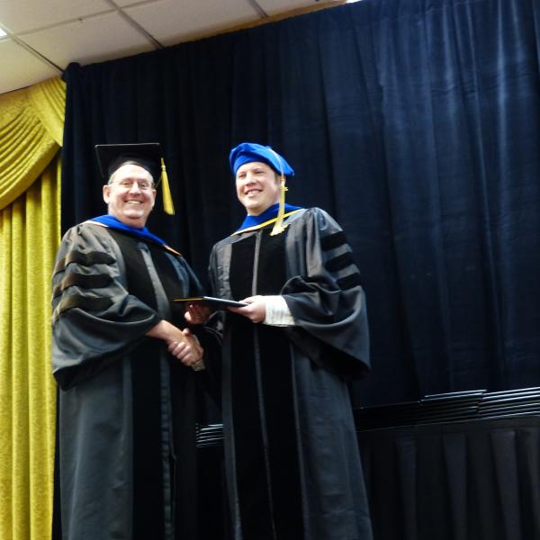 Chair, Carl Koval congratulating Ph.D. graduate Adam Csakai