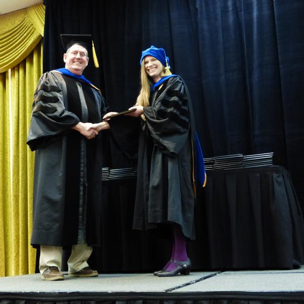 Chair, Carl Koval congratulating Ph.D. graduate Amanda Grennell