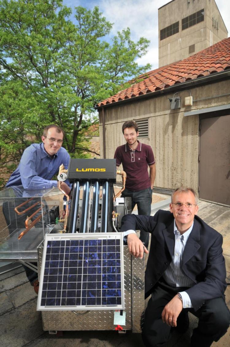 Three men stand around a solar panel on the CU campus