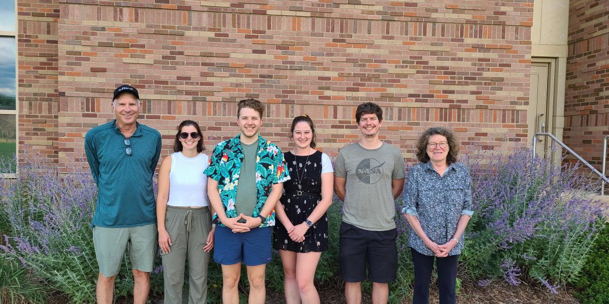 6 people standing in front of a brick wall