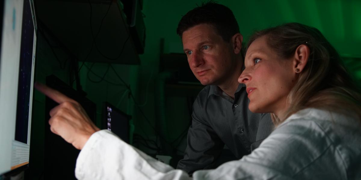 Two people pointing to a computer screen and discussing