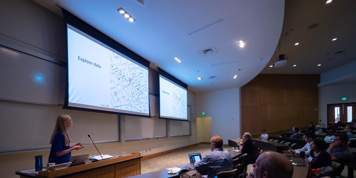 An audience watching a presentation with the words Explore Data on the screen
