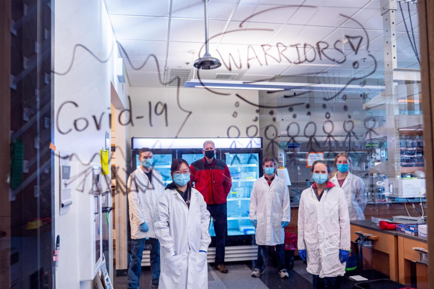 A group of scientists in lab coats and face masks.
