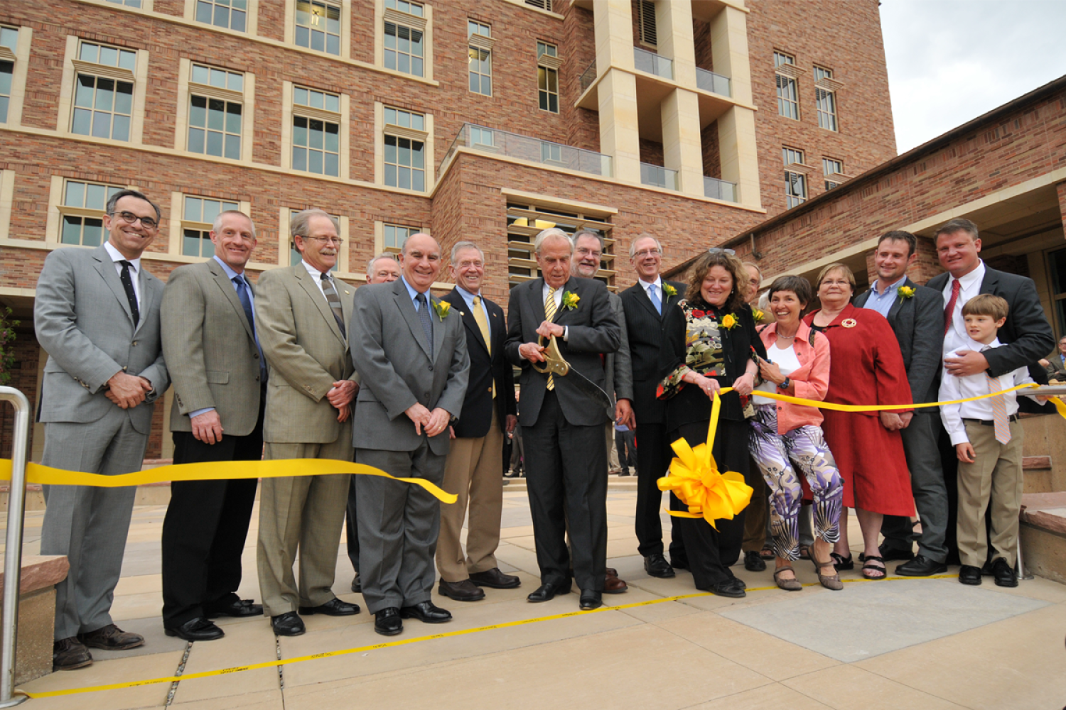 A group of people cutting a yellow ribbon in front of the Jennie Smoly Caruthers Biotechnology Building at CU Boulder