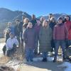 A group of people in winter coats standing in front of mountains