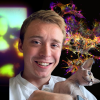 Headshot of a smiling man holding a cat with a colorful silhouette of the Mona Lisa and array of cells in the background