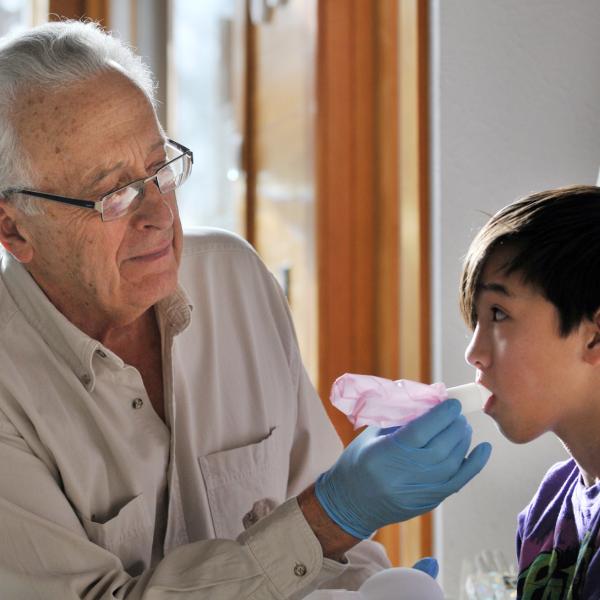 Bob Sievers, left, with help from his 11-year-old grandson, Benjamin Louis Sievers, demonstrates how vaccines can be delivered by inhaling from a bag.