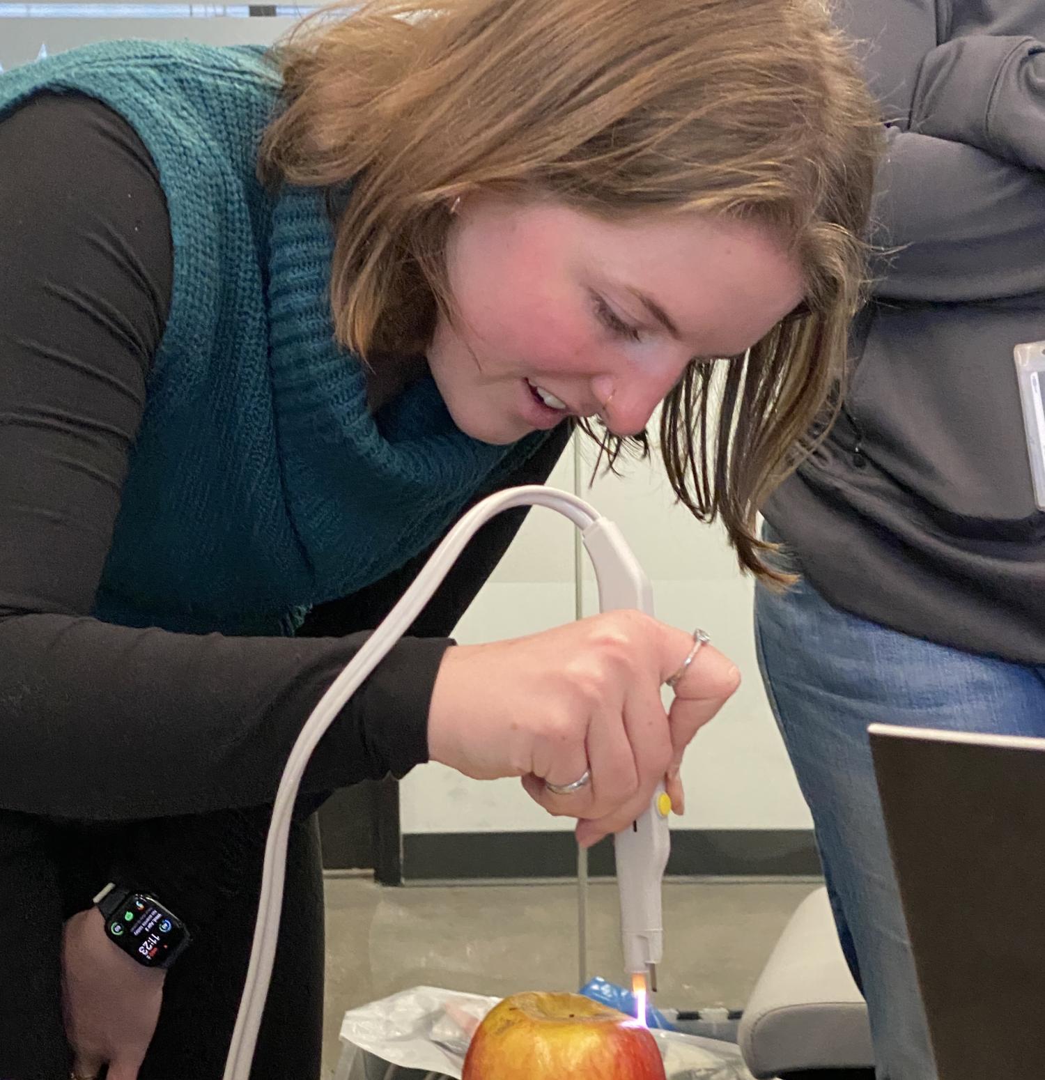 CU Boulder alum Mia Fox testing the argon beam module on an apple