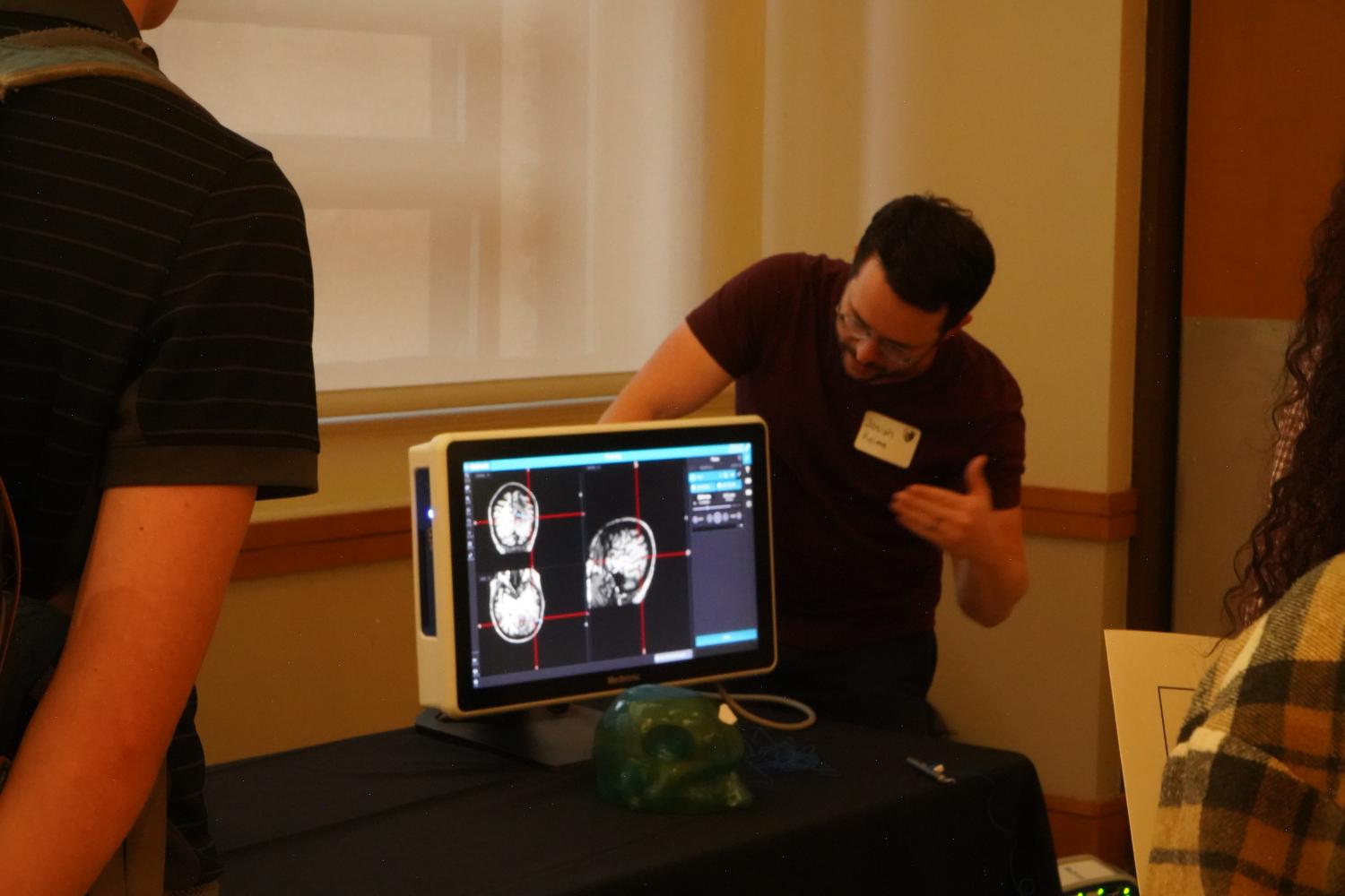 A man pointing at medical models on a computer screen as others watch