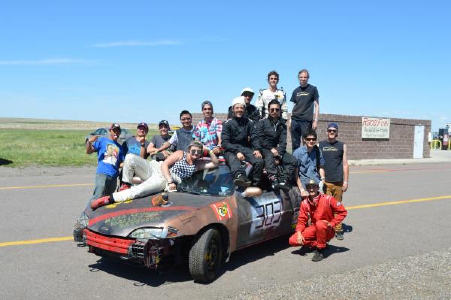Race participants sitting on one of the cars. 