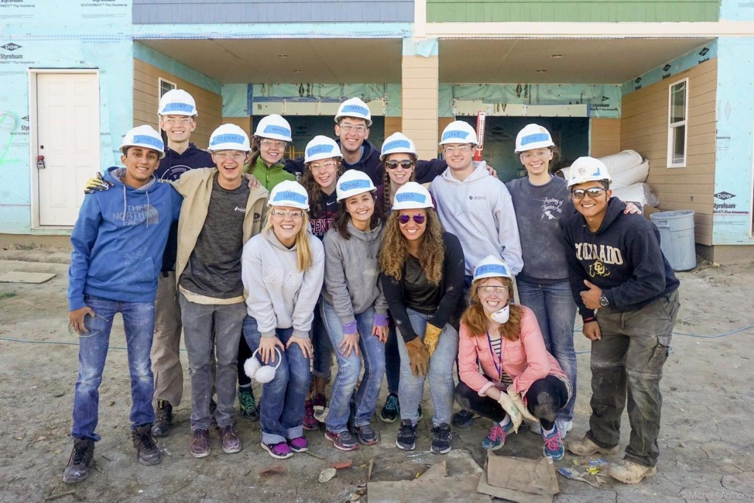 Students posing in front of a house they helped work on.