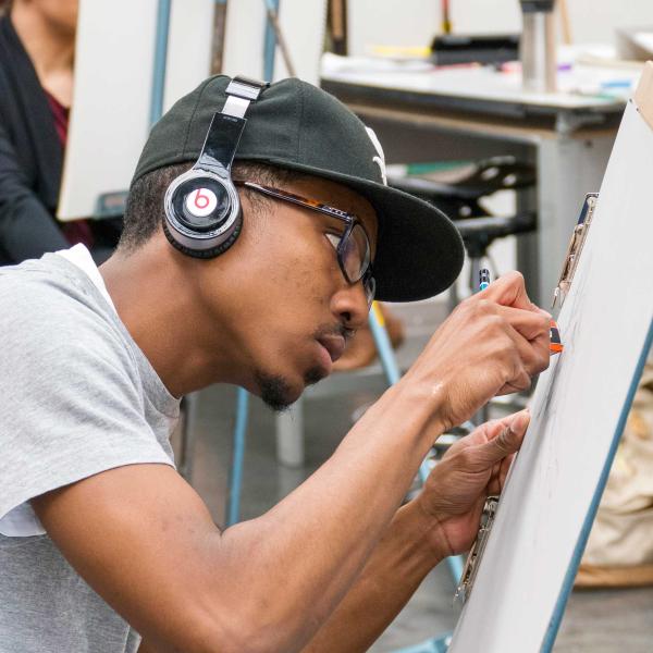 Art student listening to headphones while working on a canvas