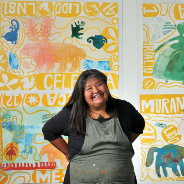 CU Boulder art professor Melanie Yazzie is photographed in front of one of her prints. Use spontaneity and interactions with your subject to create engaging portraits.