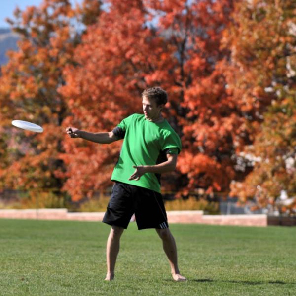 A student plays Frisbee on a fall day. Capture environment when it helps tell the story.