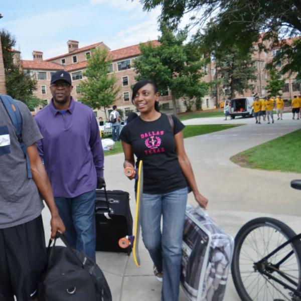 A family helps a new student on move-in day. Capture action when possible. Be mindful of branding or logos on shirts.
