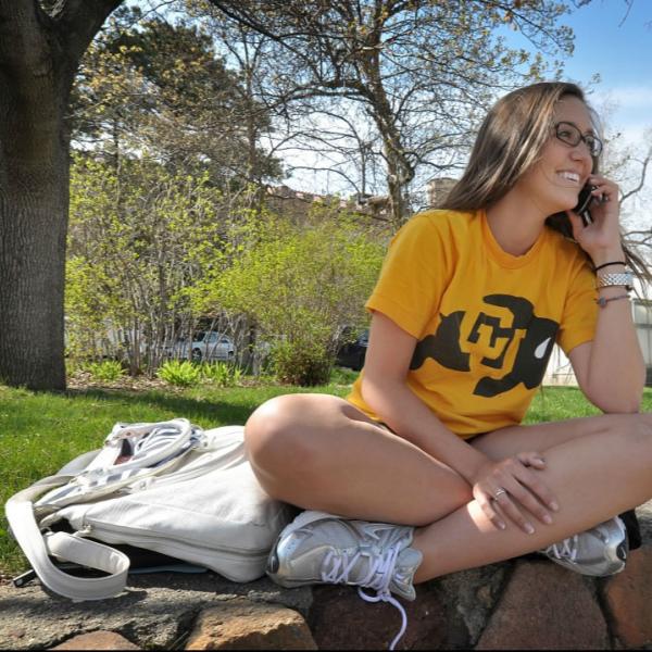 A student enjoys a spring day outdoors. CU Boulder logos are good to capture in photos.