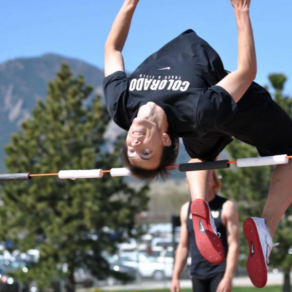 A track student participates in the high jump. When possible, frame the flatirons in photos.