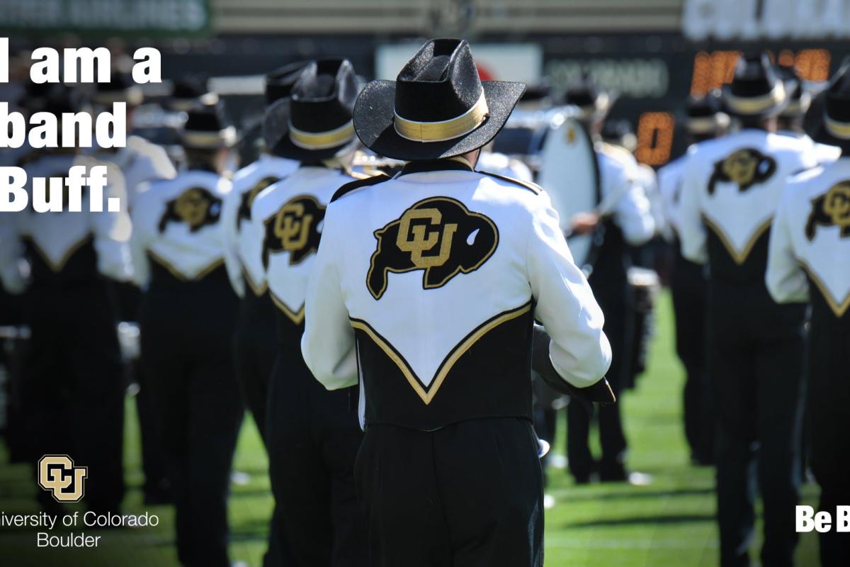 The back of band members in formation on a field with "I am a band Buff"
