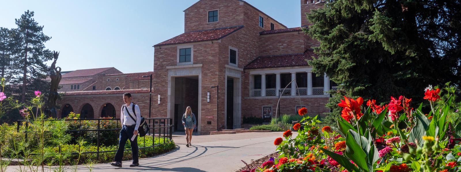 Students walking on campus as flowers bloom.