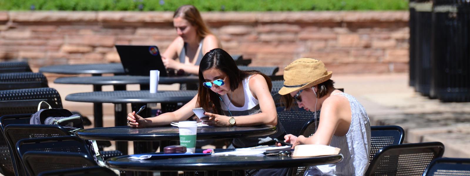 Students enjoying sunshine at picnic tables
