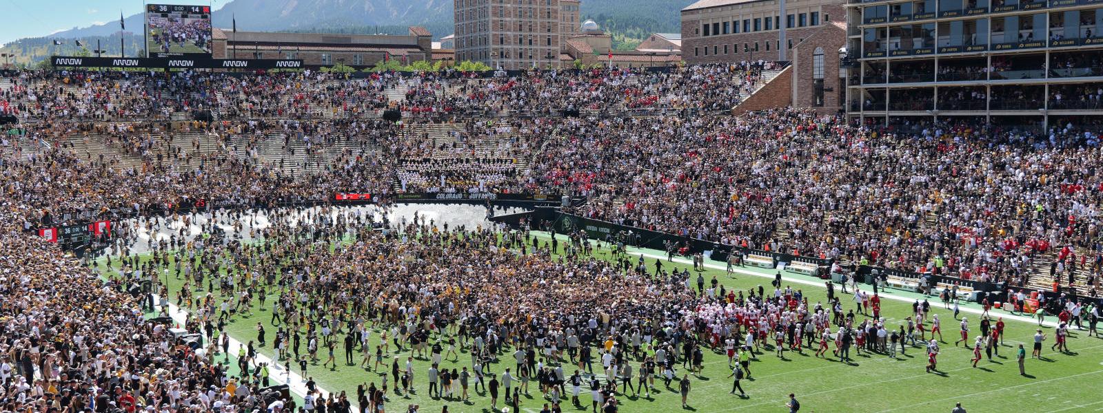 Stadium crowd congregating on football field.