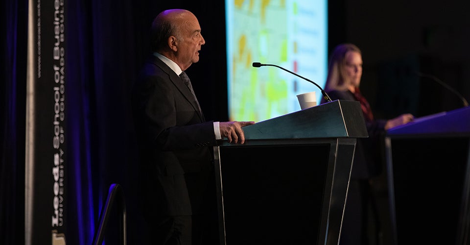 Two speakers at separate podiums onstage at the forum in 2022.