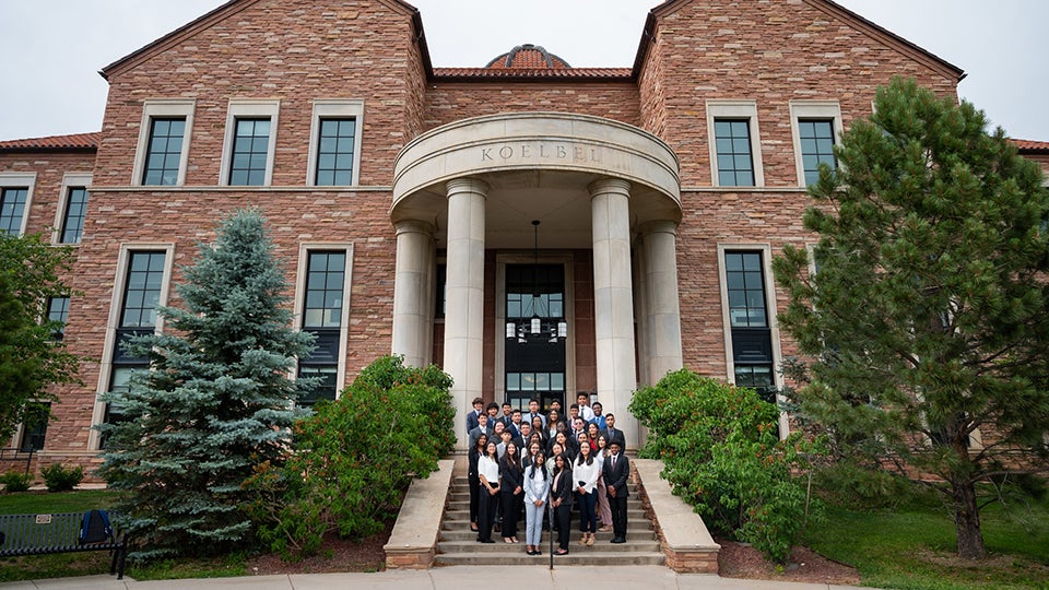 Participants in the 2022 KeyBank Business Leadership Program pose in professional attire outside of the Koelbel Building