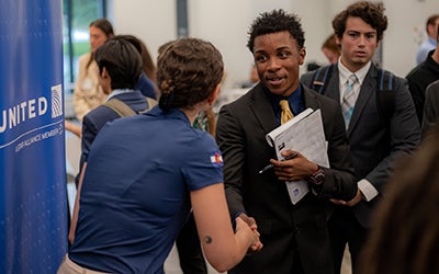 A student shakes hands with a recruiter at a networking session.