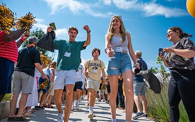 New students walk as parents cheer them on at orientation.