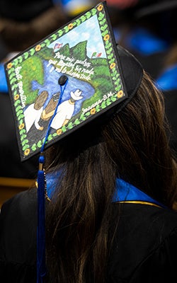 View from behind a first-generation student who has decorated her graduation cap.