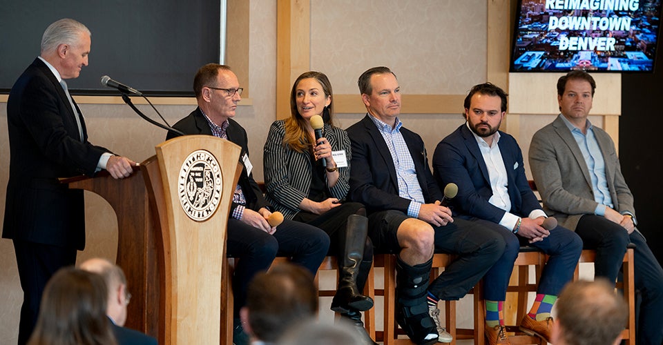 A group of professionals at a podium in front of a packed room.