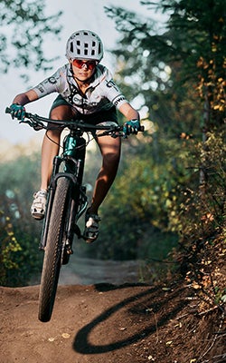 A woman goes over a jump on her mountain bike.