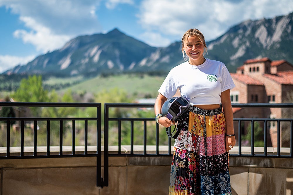 Emily Campbell stands on the Koelbel Building deck with the Flatirons in the background.